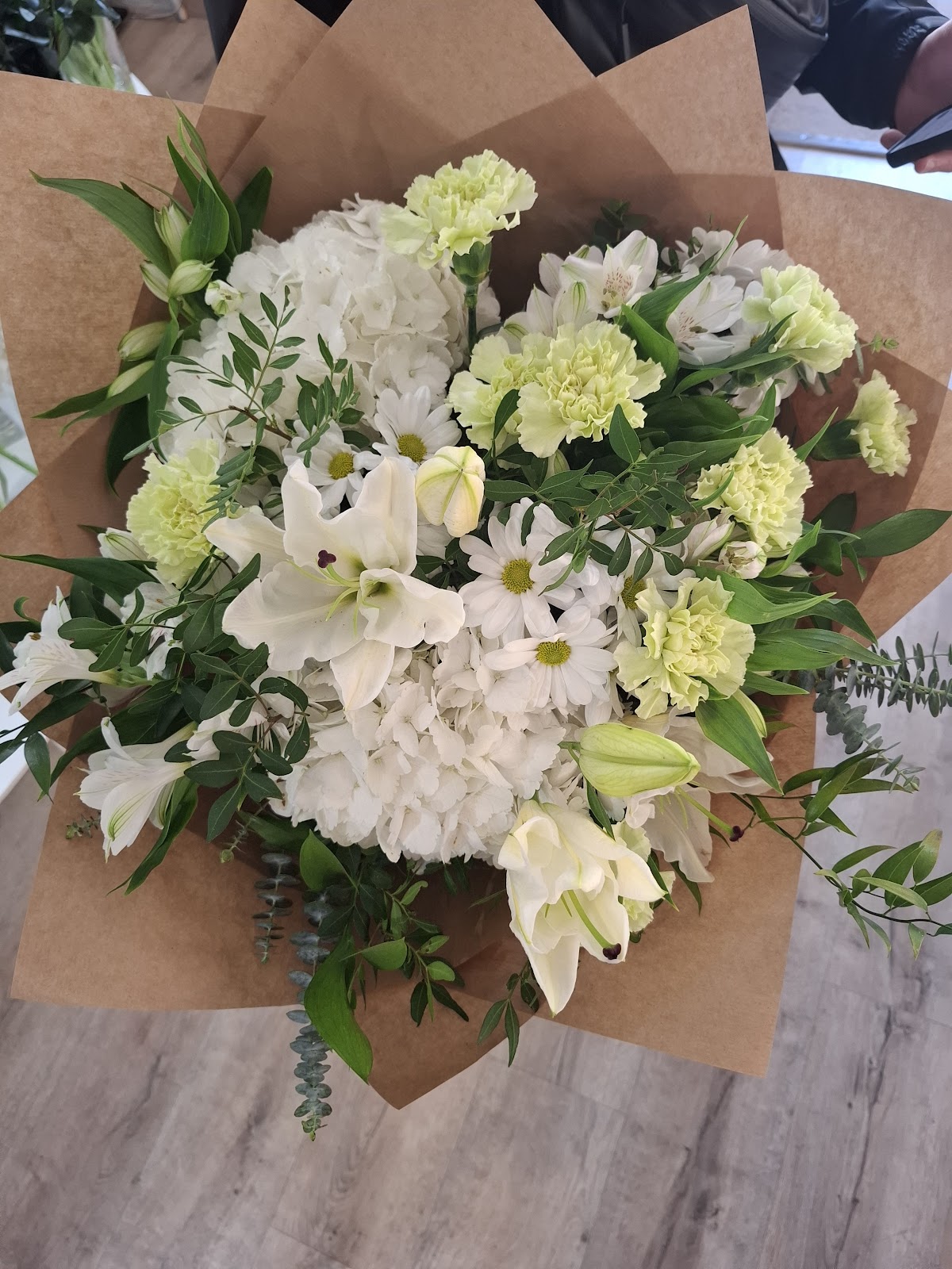 Bouquet elegante de lilium blancos, claveles verdes y eucalipto sobre envoltorio kraft